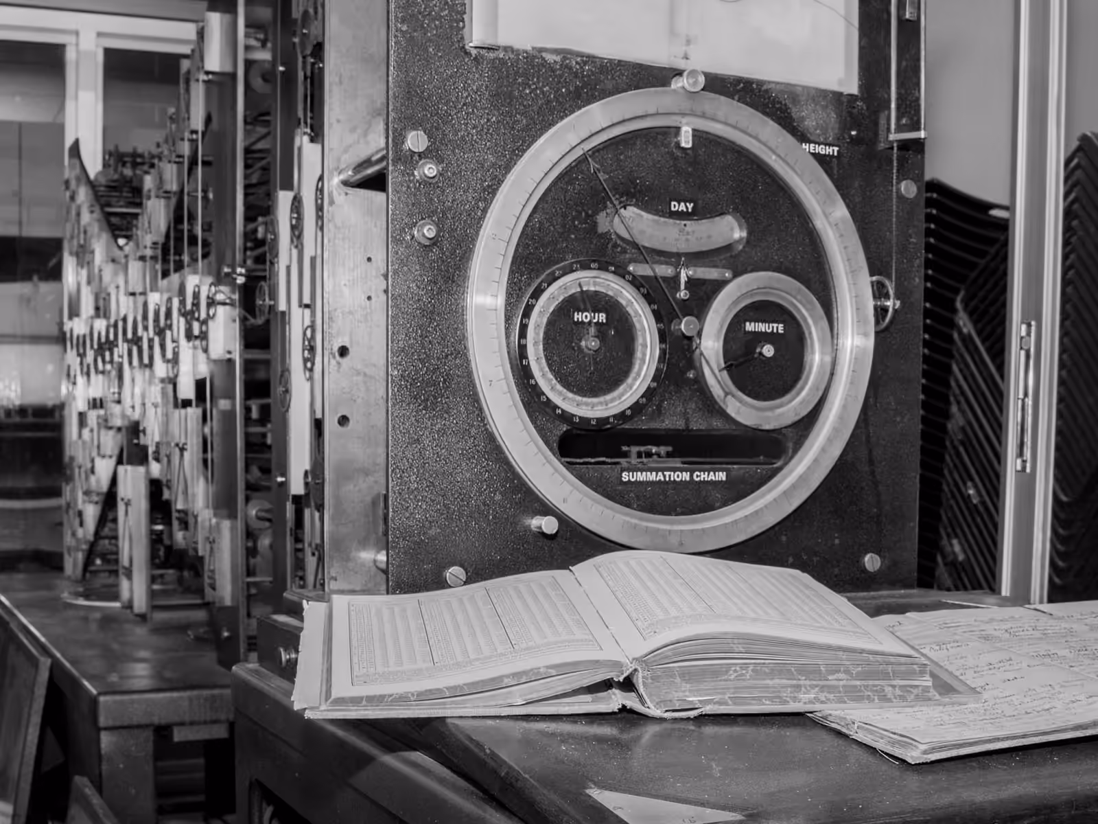 Tide Predicting Machine No. 2, its brass dials above an open ledger of computed tides.